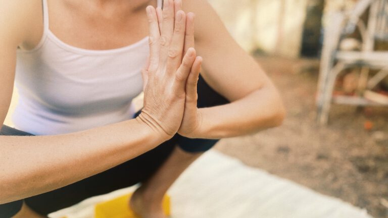 Nina Raem beim Yin Yoga online in der Yogastellung "die Hocke" mit Händen vor dem Herzen