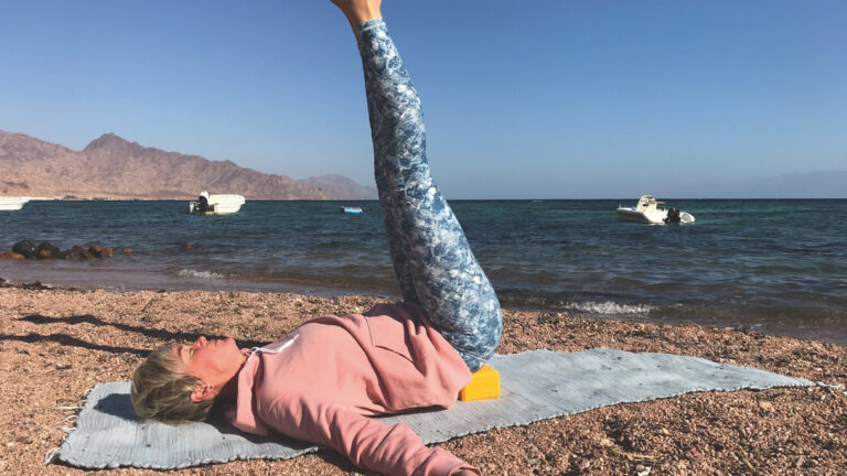 Yin Yoga für Freedivers | Yogaposition viparita karani | auf dem Rücken liegend, Klotz als Unterstützung unter der Kreuzbeinplatte, Beine nach oben Richtung Himmel gestreckt, Arme neben dem Körper