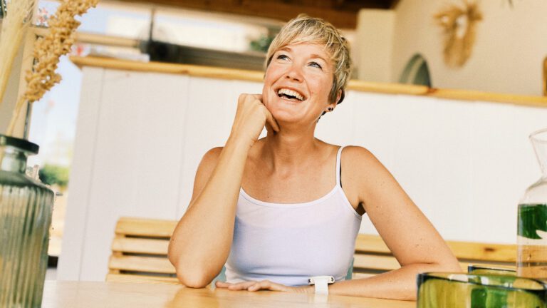 Portrait Nina Raem sitzend mit Lächeln im Gesicht