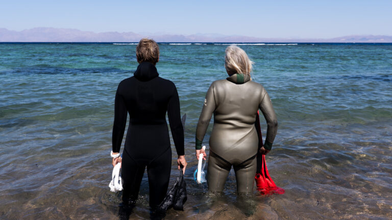 Open Water Coaching Freediving: Instruktorin und Schülerin gehen mit Equipment zusammen ins Wasser fürs Tieftauchen in Dahab, Ägypten